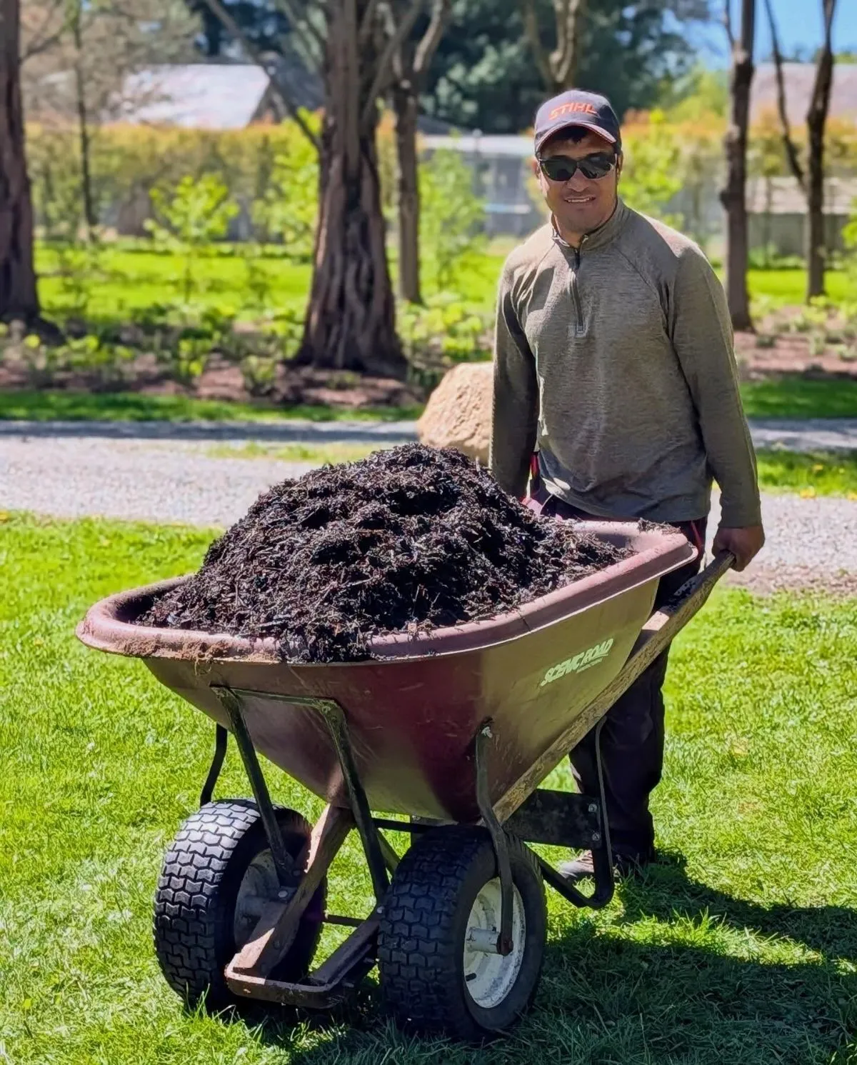 Volunteer doing landscaping at animal rescue A person pushing a wheelbarrow of mulch for animal shelter landscaping
